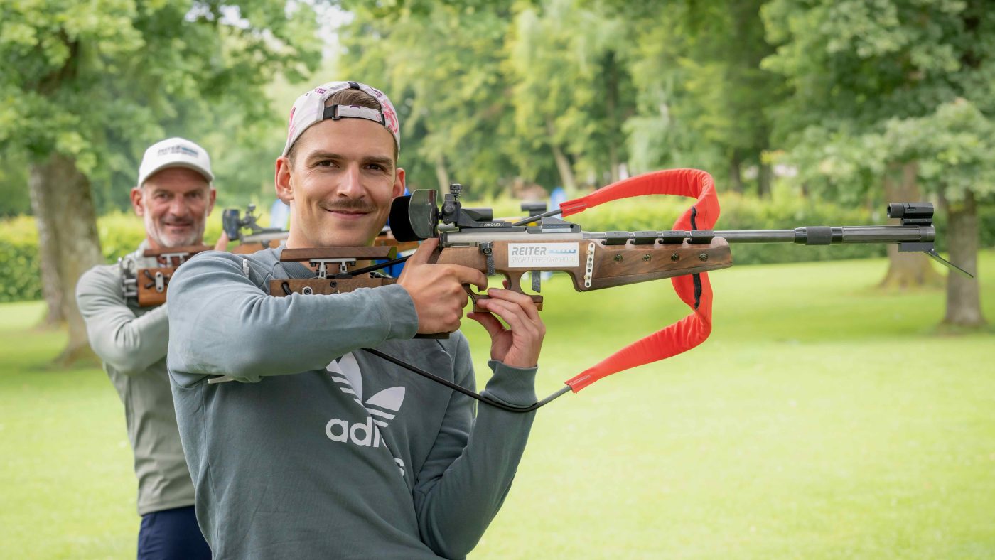 Dominic Reiter beim Sommerbiathlon mit Biathlongewehr, im Hintergrund Ernst Reiter